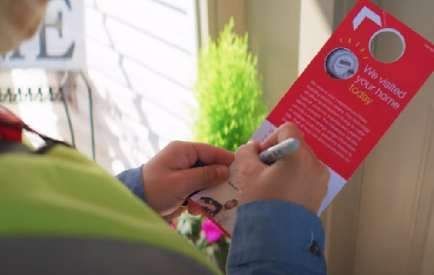 A technician  leaves a door hangar after changing a meter.
